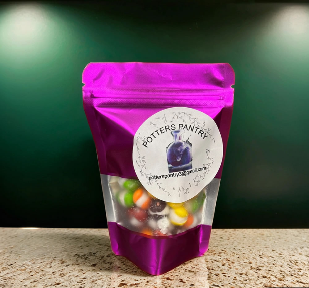 A purple plastic pouch labeled "Potters Pantry" containing colorful candy, displayed on a granite countertop.